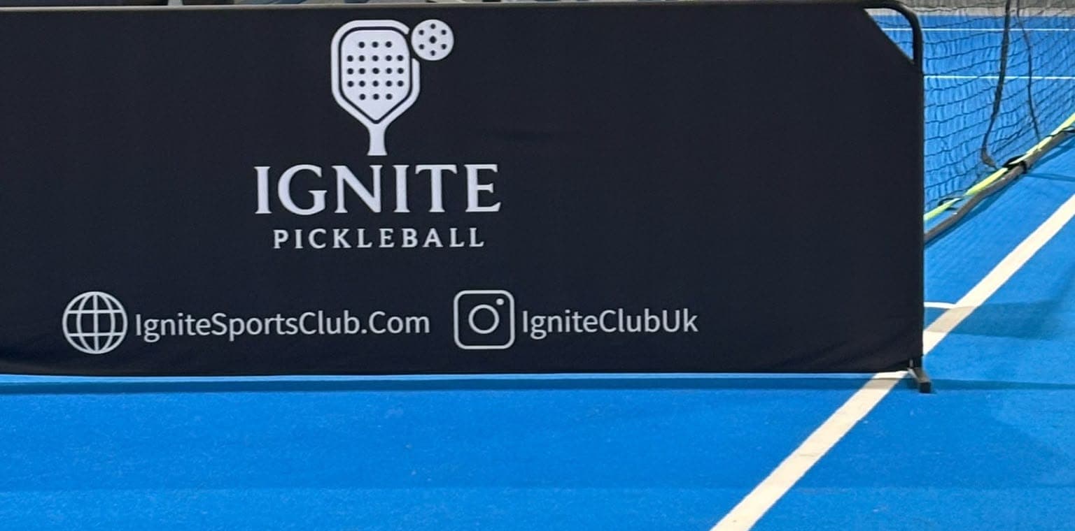 A black Ignite court banner standing on the blue court