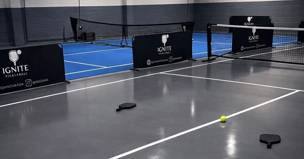 The grey pickleball court at Ignite with paddles and a ball on the centre line