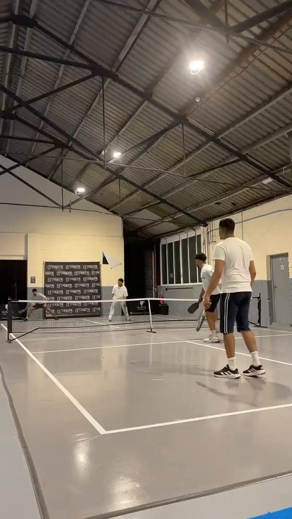 An evening game of pickleball on the grey court at Ignite, under the hall lights